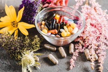 pharmacological pills and blooming flowers on wooden tabletop, alternative medicine concept clipart