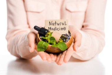 cropped image of woman holding bowl with essential oil and natural medicine sign isolated on white clipart