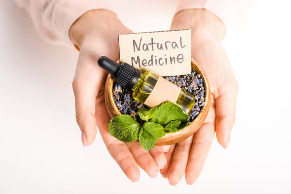 cropped image of woman holding bowl with essential oil and natural medicine sign isolated on white