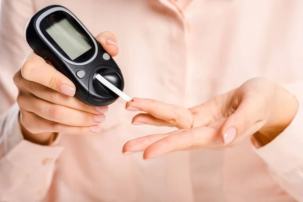 ホワイト 糖尿病概念に分離された Glucometer と血液中のブドウ糖のレベルを測定女性のトリミングされた画像 — ストック写真