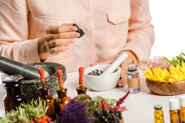 cropped image of woman adding essential oil to natural medicines isolated on white