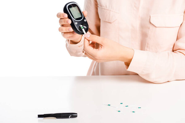 cropped image of woman putting strip into glucometer isolated on white, diabetes concept