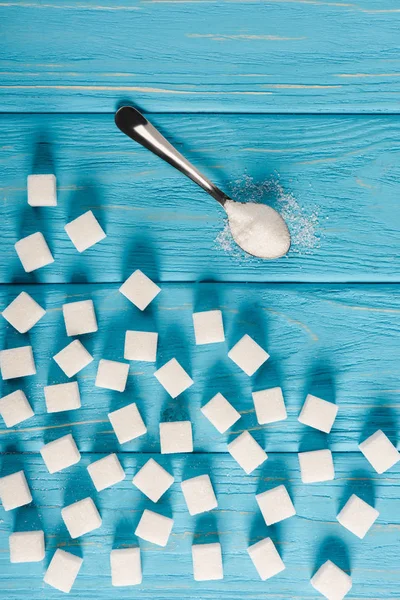 在木质天蓝色桌面上的粉和精制糖的顶部视图 糖尿病概念 — 图库照片
