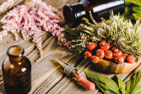 glass jars and flowers on wooden tabletop, alternative homeopathy medicine concept