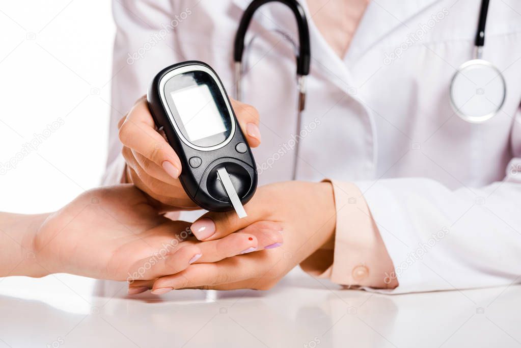 cropped image of doctor measuring patient level of glucose in blood with glucometer isolated on white, diabetes concept