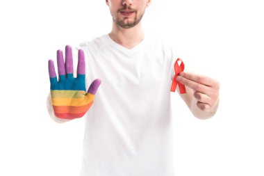 cropped image of homosexual man with hand painted in rainbow holding red ribbon isolated on white, world aids day concept clipart