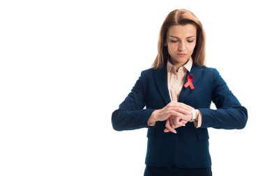 attractive businesswoman with red ribbon on suit checking time isolated on white, world aids day concept clipart