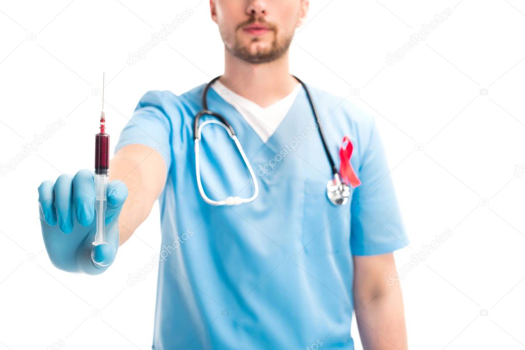 cropped image of doctor with red ribbon on uniform showing syringe with blood isolated on white, world aids day concept