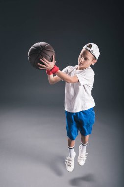 şık çocuk gri arka plan üzerinde basketbol oynarken