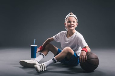 gri zemin üzerine soda içmek ve basketbol topu ile varoluş boy gülümseyerek