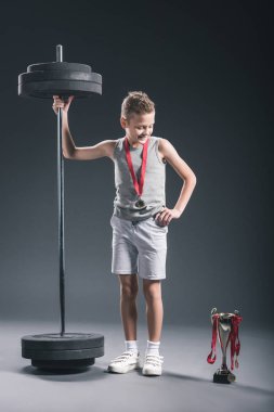 halter ve Şampiyonlar Kupası'nda koyu zemin üzerinde seyir madalya ile spor giyim gülümseyen çocuk