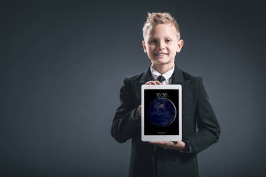 gülümseyen çocuk portresi gri zemin üzerinde elinde tablet gösterilen işadamı gibi giyinmiş