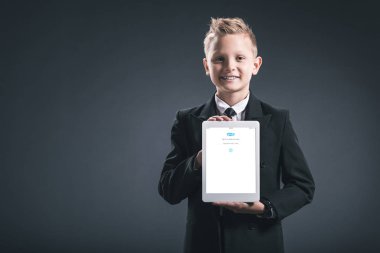 gülümseyen çocuk portresi işadamı gösteren tablet gri zemin üzerinde elinde sqype logolu gibi giyinmiş