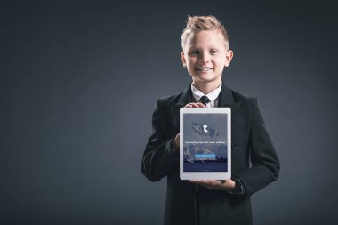 Gülümseyen çocuk portresi işadamı gösteren tablet gri zemin üzerinde elinde tumblr logolu gibi giyinmiş