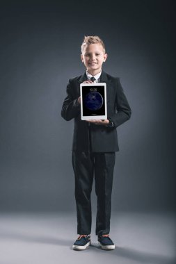 boy gülümseyerek gri zemin üzerinde elinde tablet gösterilen işadamı gibi giyinmiş