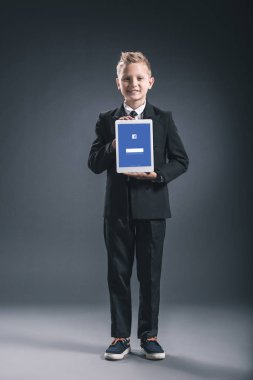 işadamı gösteren tablet eller gri zemin üzerinde facebook logosu ile boy gülümseyerek kılığında