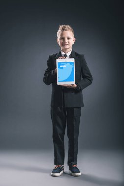 boy gülümseyerek işadamı gösteren tablet ile heyecan Web gri zemin üzerinde elinde gibi giyinmiş