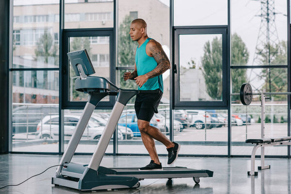 side view of young african american sportsman running on treadmill at gym