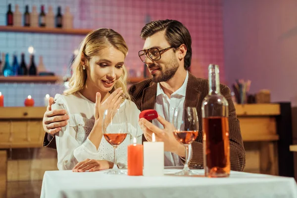 handsome man proposing to beautiful girlfriend during romantic dinner in cafe