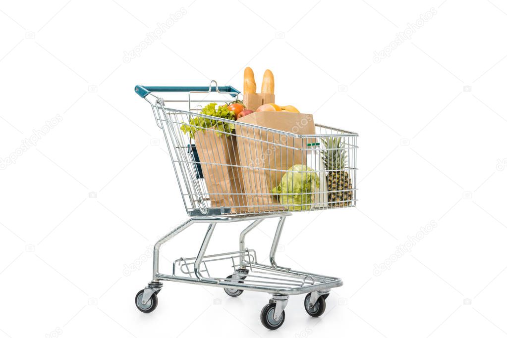 paper bags full of products in shopping trolley isolated on white
