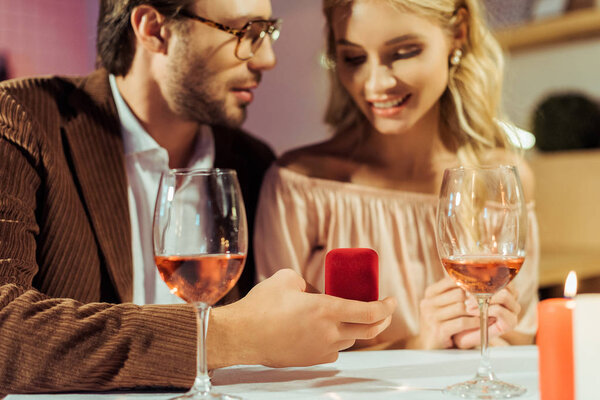 partial view of man proposing to girlfriend at table with wine glasses in restaurant 