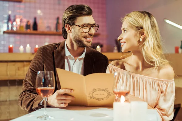 Casal Sorrindo Com Menu Olhando Para Outro Durante Jantar Romântico — Fotografia de Stock Grátis