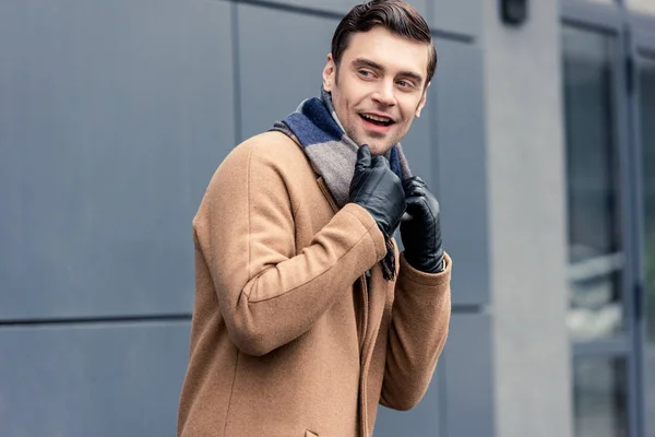 handsome smiling man in coat and scarf looking away on street