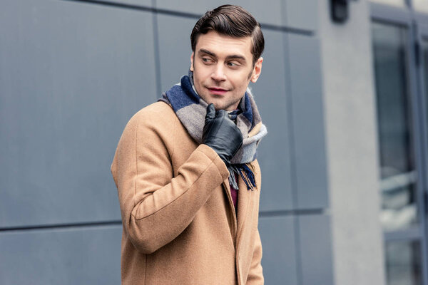 handsome man in coat and scarf looking away on street