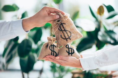partial view of people holding sackcloth bag with dollar sign in hands  clipart