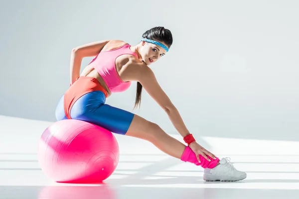 美丽的运动女孩坐在和锻炼健身球在灰色 — 图库照片