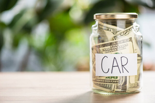 close-up view of glass jar with dollar banknotes and inscription car