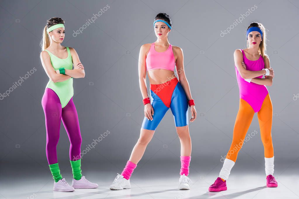 vista completa de las mujeres jóvenes atléticas en ropa deportiva de estilo  80 posando en gris 2023