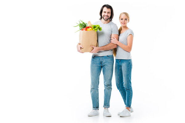 Beautiful couple with grocery bags looking at camera isolated on white