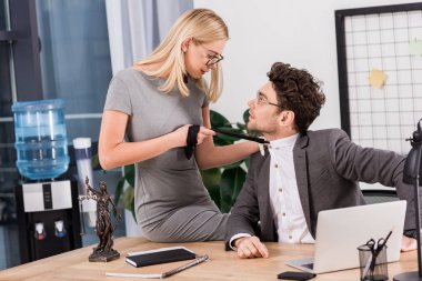 Office, office romance kavramı masada otururken genç iş kadını çekerek meslektaşları kravat