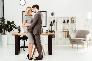 Genç avukatlar ofiste dururken birbirlerine sarılma, flört ve office romance kavramı