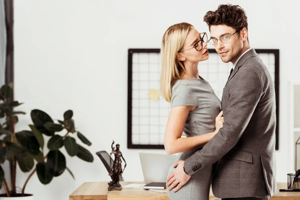年轻的律师拥抱对方 而站在办公室 调情和办公室浪漫的概念 — 图库照片