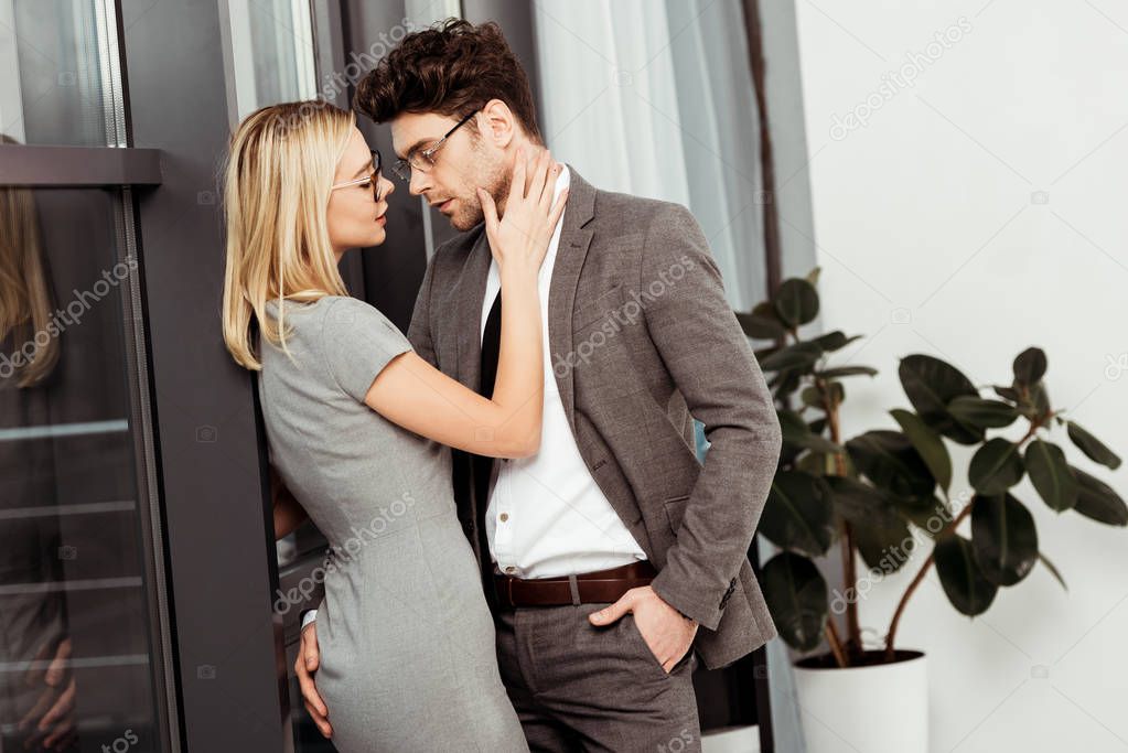 side view of businesspeople hugging looking at each other in office, flirt and office romance concept