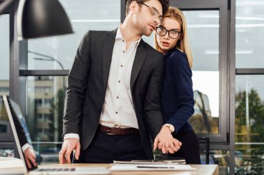 İşyerinde, office romance kavramı flört ederken el ele tutuşarak genç iş adamları