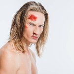 Serious angry naked man with blood on face isolated on white