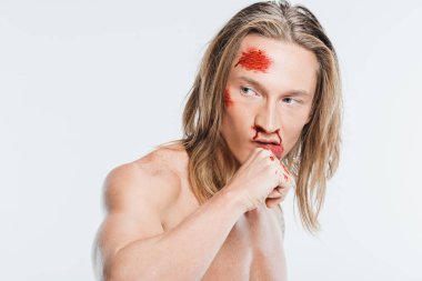 close up of adult man with bruises on face wiping off blood isolated on white clipart