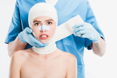  cerrah sonra plastik cerrahi üzerine beyaz izole kadın yüz bandaj ile yukarı taping eldiven