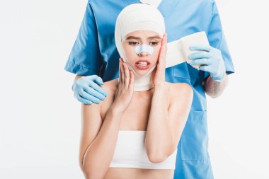  cerrah sonra plastik cerrahi üzerine beyaz izole kadın yüz bandaj ile yukarı taping eldiven