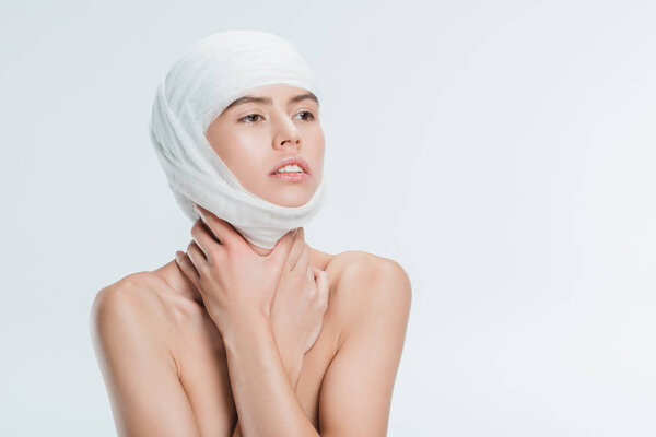 nude woman with bandages on head after plastic surgery isolated on white