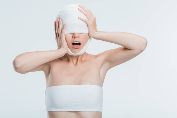 scared woman with bandages touching head isolated on white