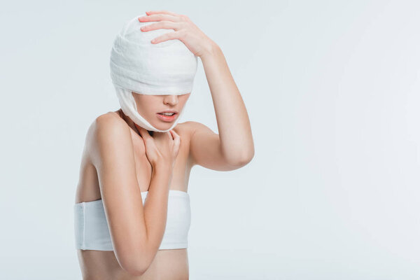 woman with bandages touching head isolated on white