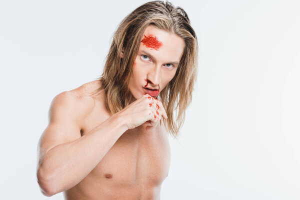 adult man with bruises on face wiping off blood isolated on white