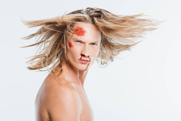 adult man with bloody bruises on face waving hair isolated on white