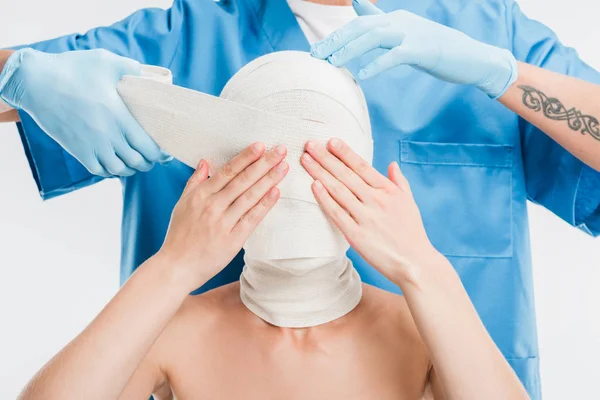 关闭整形外科医生在手套录音妇女的脸与绷带隔离在白色 — 图库照片