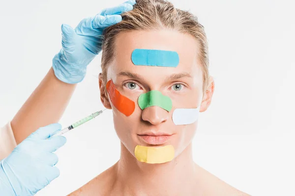 白で隔離の顔に色とりどりのパッチを持つ男に注射を行う医師  — 無料ストックフォト