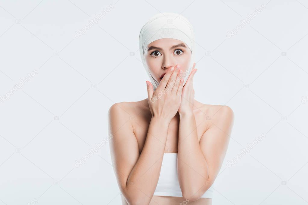 scared woman with bandages over head after plastic surgery isolated on white